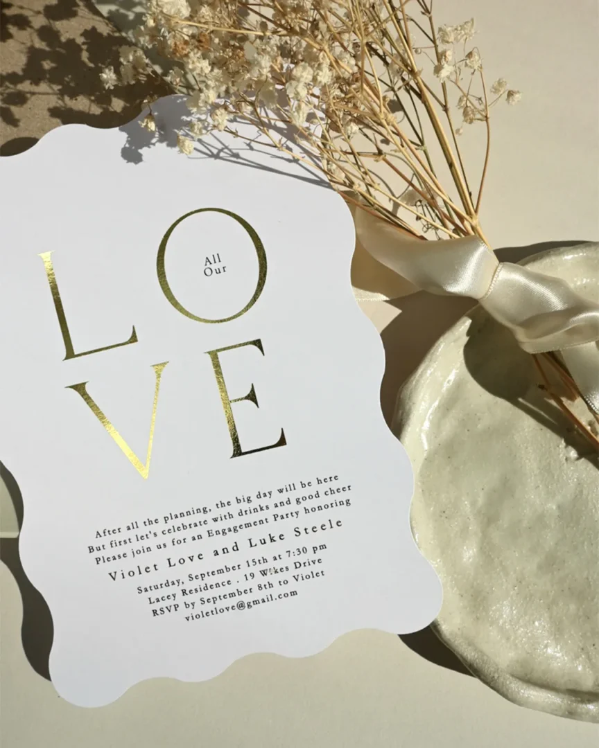 Gold flat foil LOVE text on white wedding invitation with wavy die-cut edge