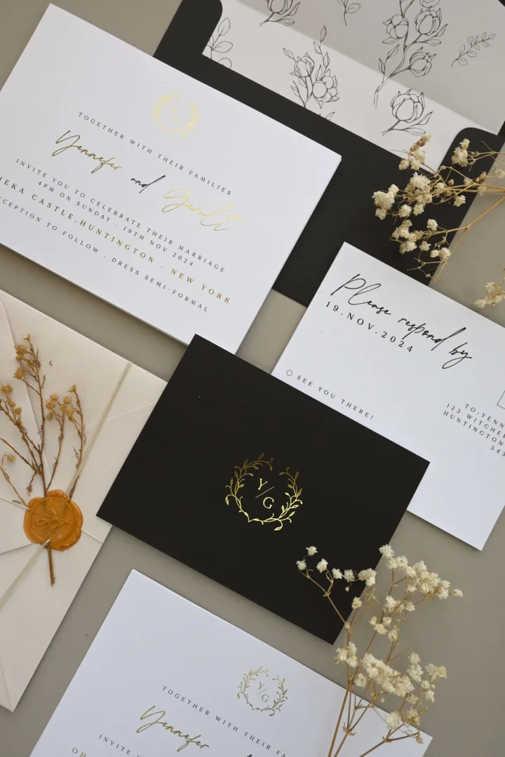 White wedding invitation with gold flat foil script names and wreath monogram crest