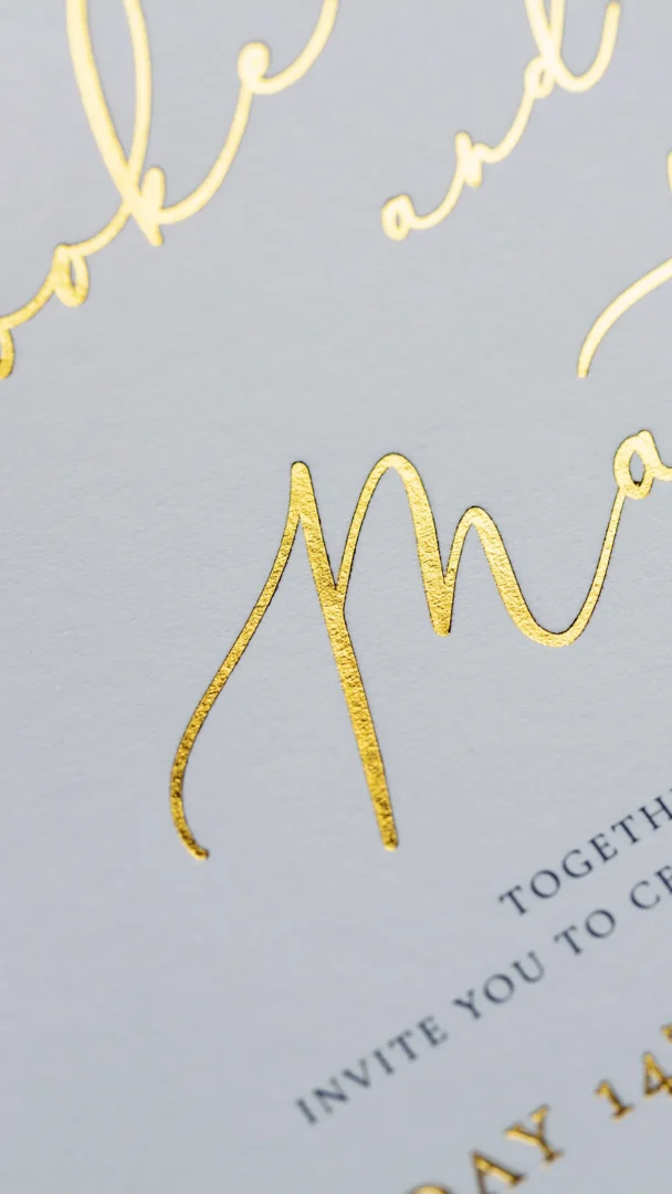 Macro close-up of gold foil stamp calligraphy showing debossed impression in paper