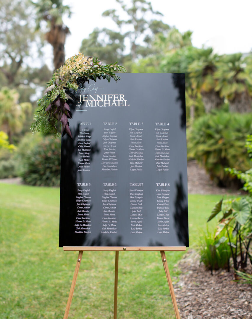 Acrylic wedding seating chart displayed outdoors in garden setting