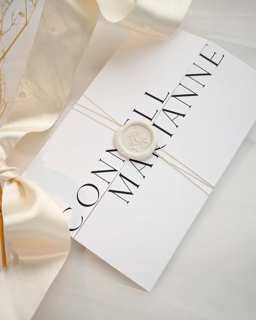 scroll wedding invitation tied with satin ribbon and wax seal - flat lay on linen surface wedding stationery