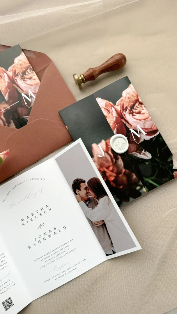 Spring wedding invitation flat lay with botanical floral design in terracotta and sage on cream paper