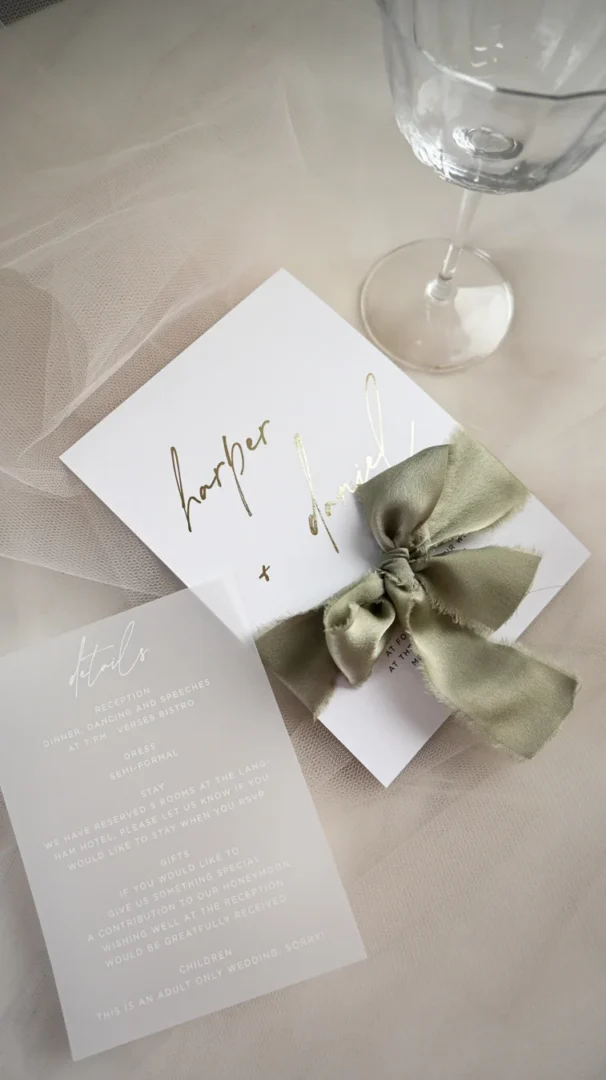 Paperlust wedding invitation suite dressed with velvet ribbon bow in deep burgundy showing tied detail close-up