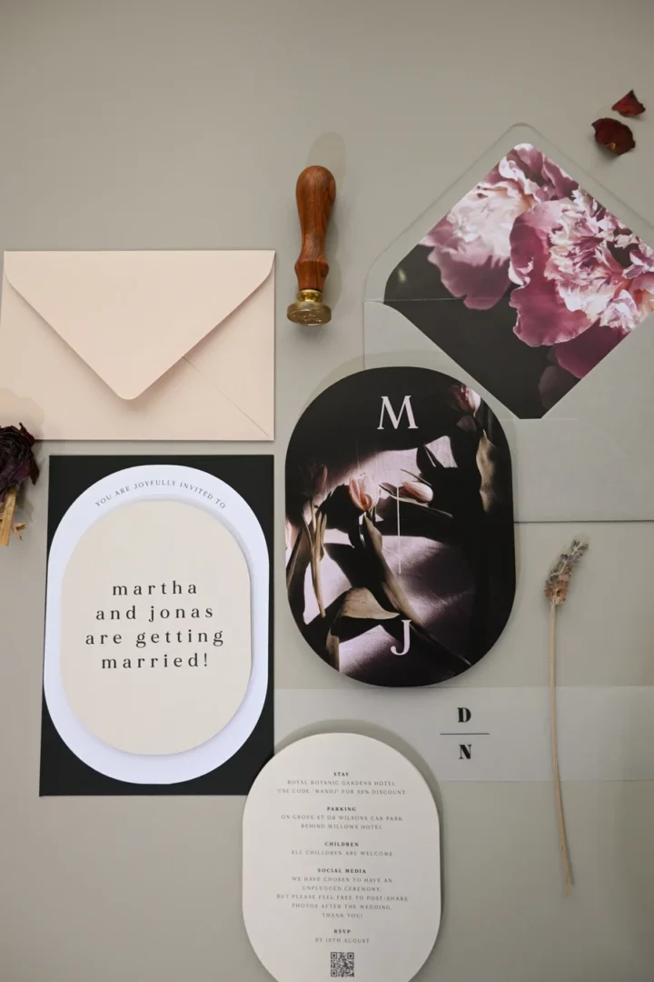 A flat-lay of soft blush and cream bridal shower invitations with floral illustration, ribbon, and wax seal on a marble surface, editorial product photography wedding stationery