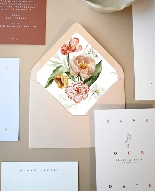 A phone screen showing a stylish digital save the date design displayed flat alongside floral props and stationery on a light marble surface wedding stationery