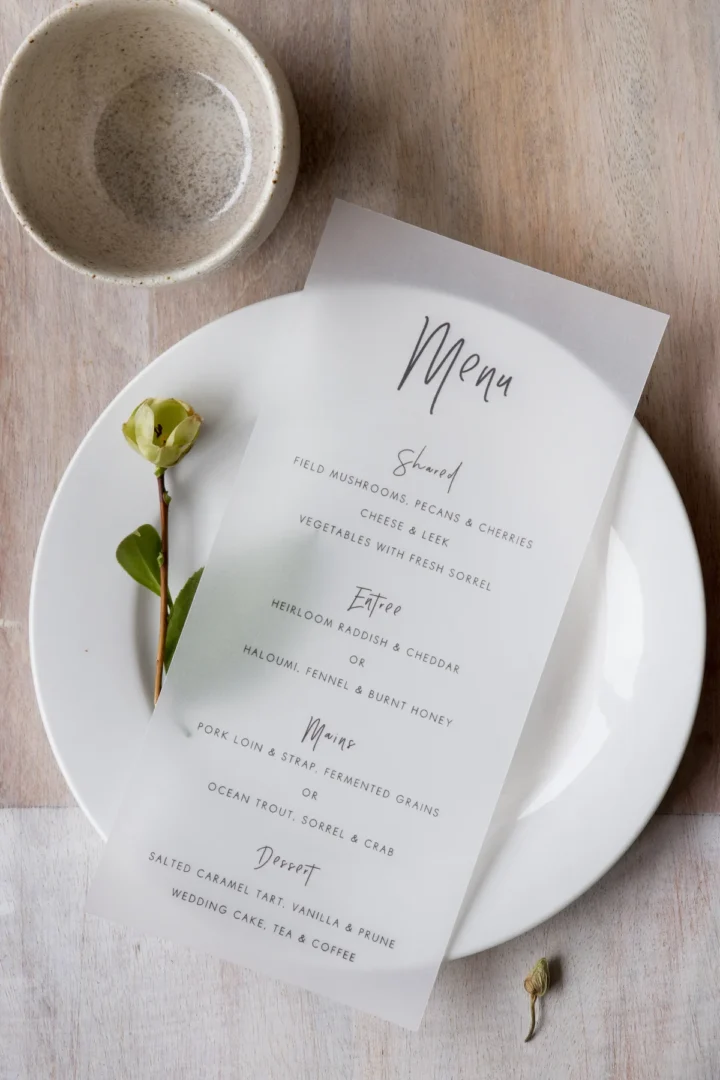 close-up of hands engraving a wooden cutting board with a wedding date and couple's names, workshop setting with sawdust and tools in soft focus background wedding stationery