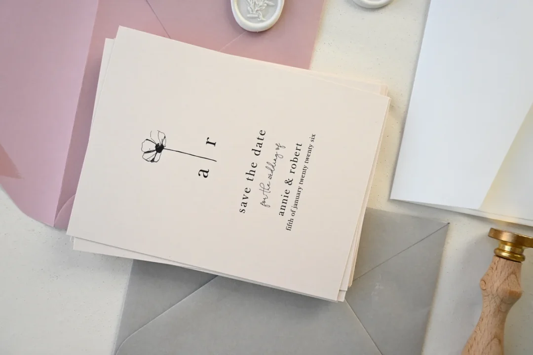 elegant wedding stationery suite with anniversary card, envelope with wax seal, flat lay on white linen, gold accents and soft floral elements wedding stationery