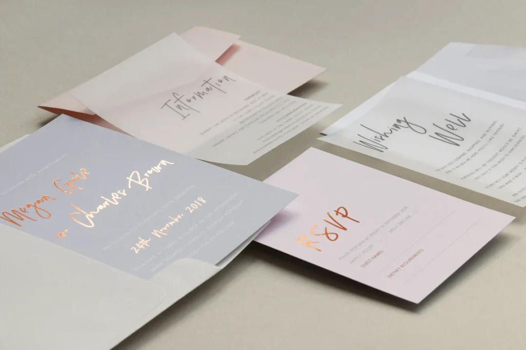 fanned stack of ivory RSVP reply cards with a single USPS Love Forever stamp affixed to each, resting on a dusty pink linen surface wedding stationery