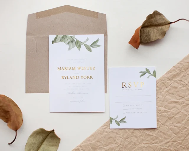 overhead flatlay of USPS Love 2026 and Wedding Blooms stamp sheets arranged on ivory linen beside a sealed wedding invitation envelope with a calligraphed address and a sprig of eucalyptus wedding stationery
