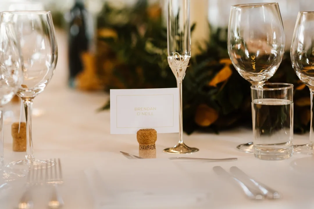 silver-haired couple in formal attire sharing a champagne toast at an elegantly set golden anniversary dinner table adorned with yellow roses and gold candelabra wedding stationery