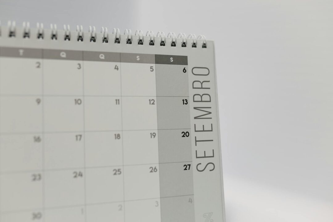 open weekly planner or calendar with 'send birth announcements' handwritten across the 5-week mark, baby items in soft focus background