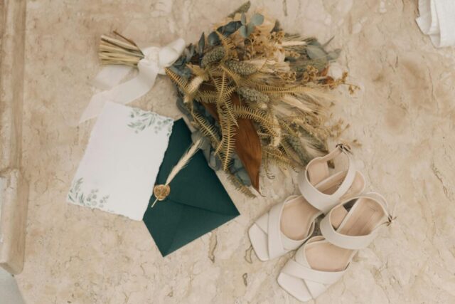 Flat-lay of bridal hair accessories on a white marble surface including a pearl-embellished comb, crystal-studded hairpins, a delicate hair