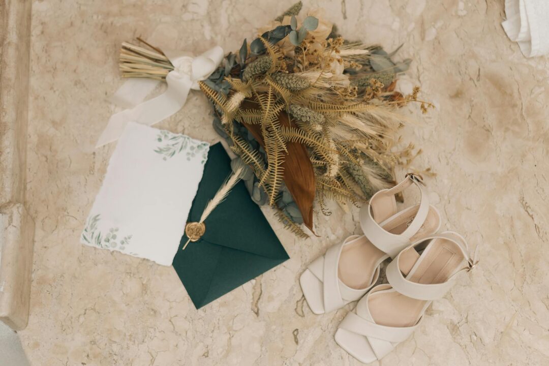 Flat-lay of bridal hair accessories on a white marble surface including a pearl-embellished comb, crystal-studded hairpins, a delicate hair