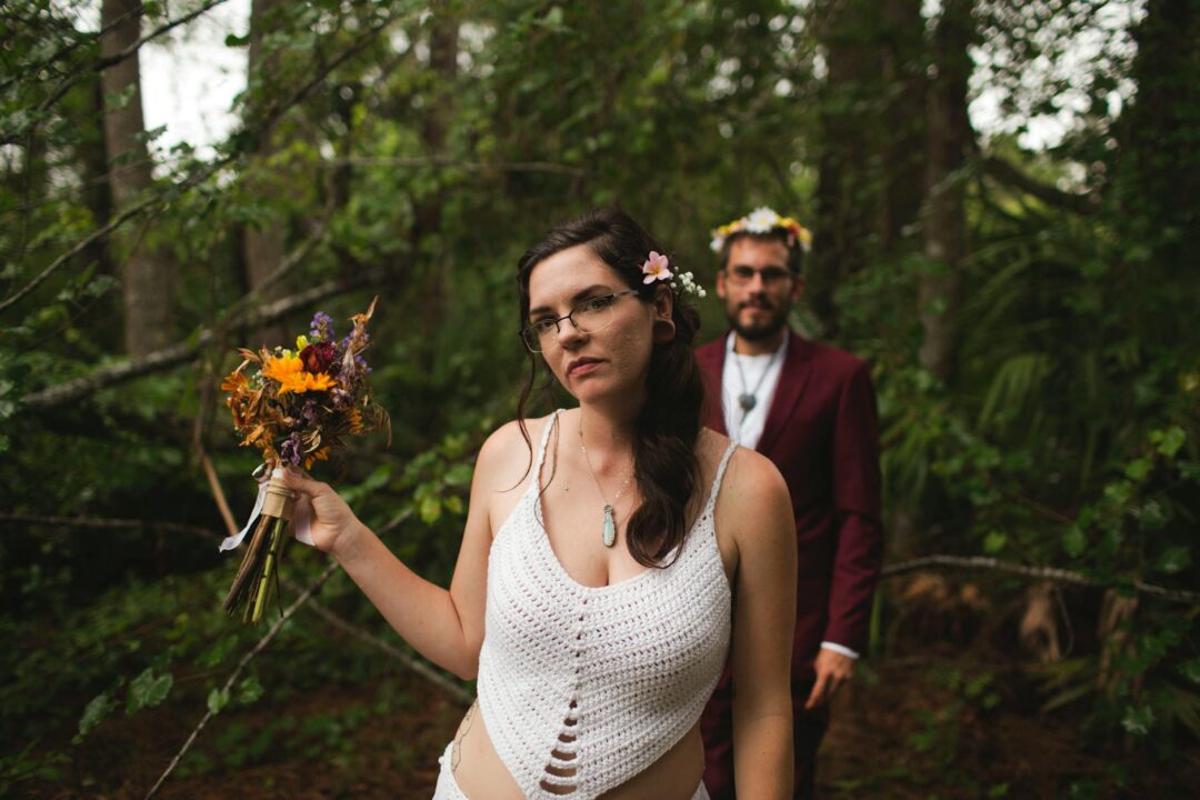 Bride outdoors with a dried flower crown featuring pampas grass, preserved eucalyptus, and blush dried roses, photographed with a garden cer