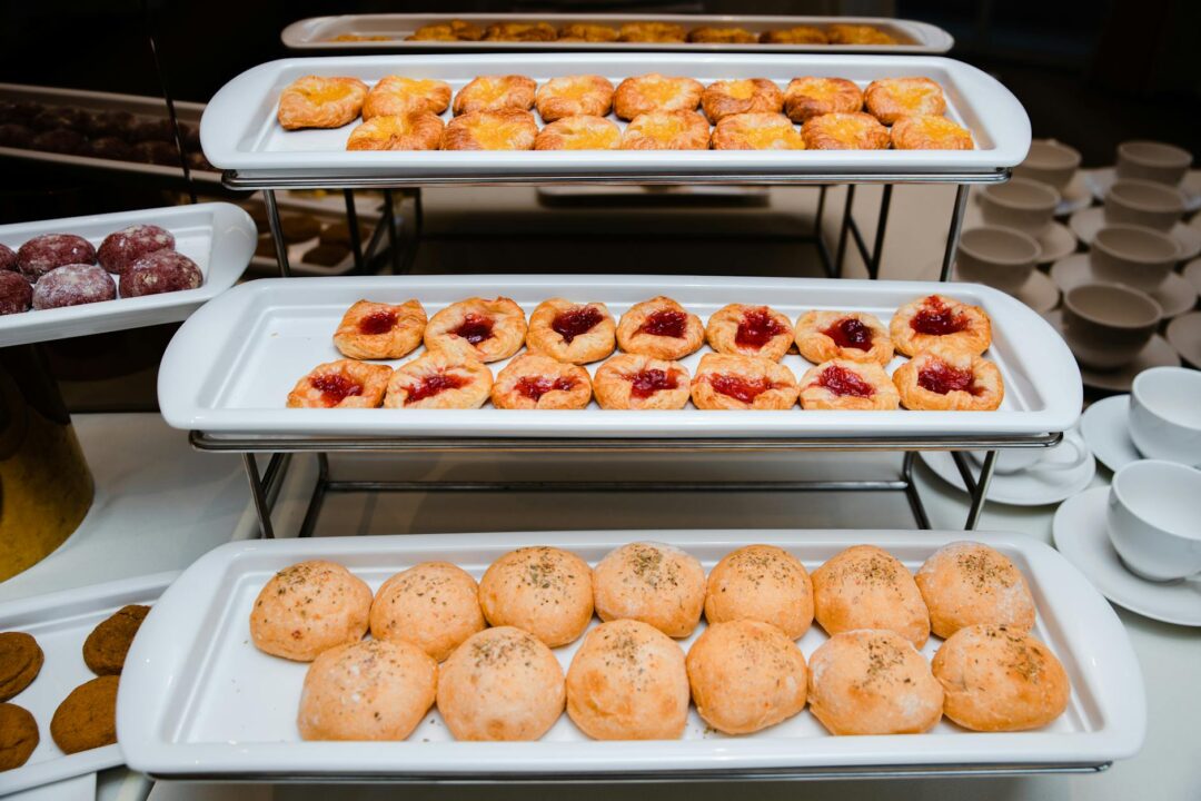 wedding brunch buffet station with pastries, smoked salmon platter, mini quiches, fresh fruit, and flower arrangement