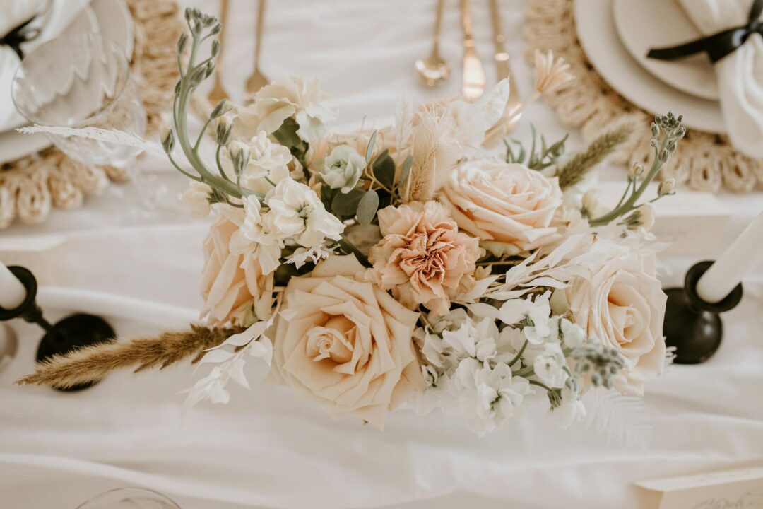 styled daytime wedding reception table with pastel floral centerpiece, place settings, printed menu cards, and warm natural light
