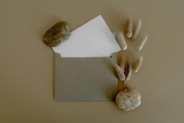 Elegant wedding invitation suite flatlay on a neutral linen surface showing invitation card, envelope with wax seal, and details card arrang