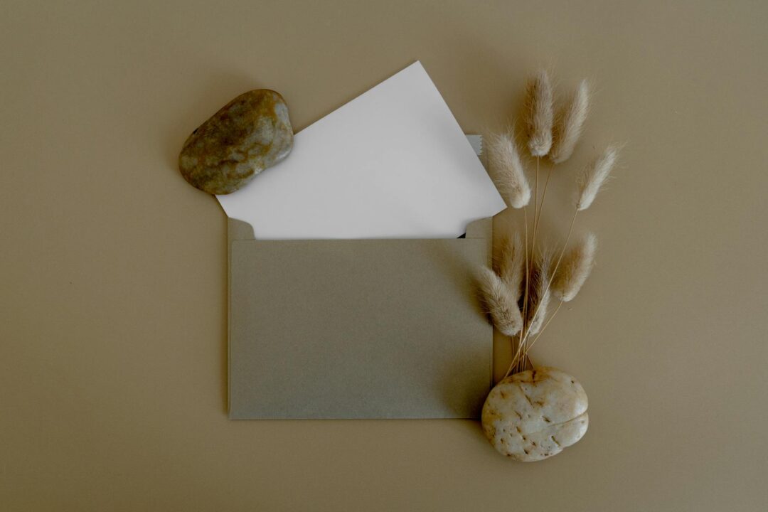 Elegant wedding invitation suite flatlay on a neutral linen surface showing invitation card, envelope with wax seal, and details card arrang