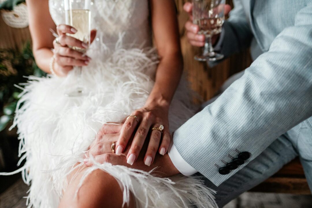 Close-up of bride and groom's hands and champagne at an elegant wedding.