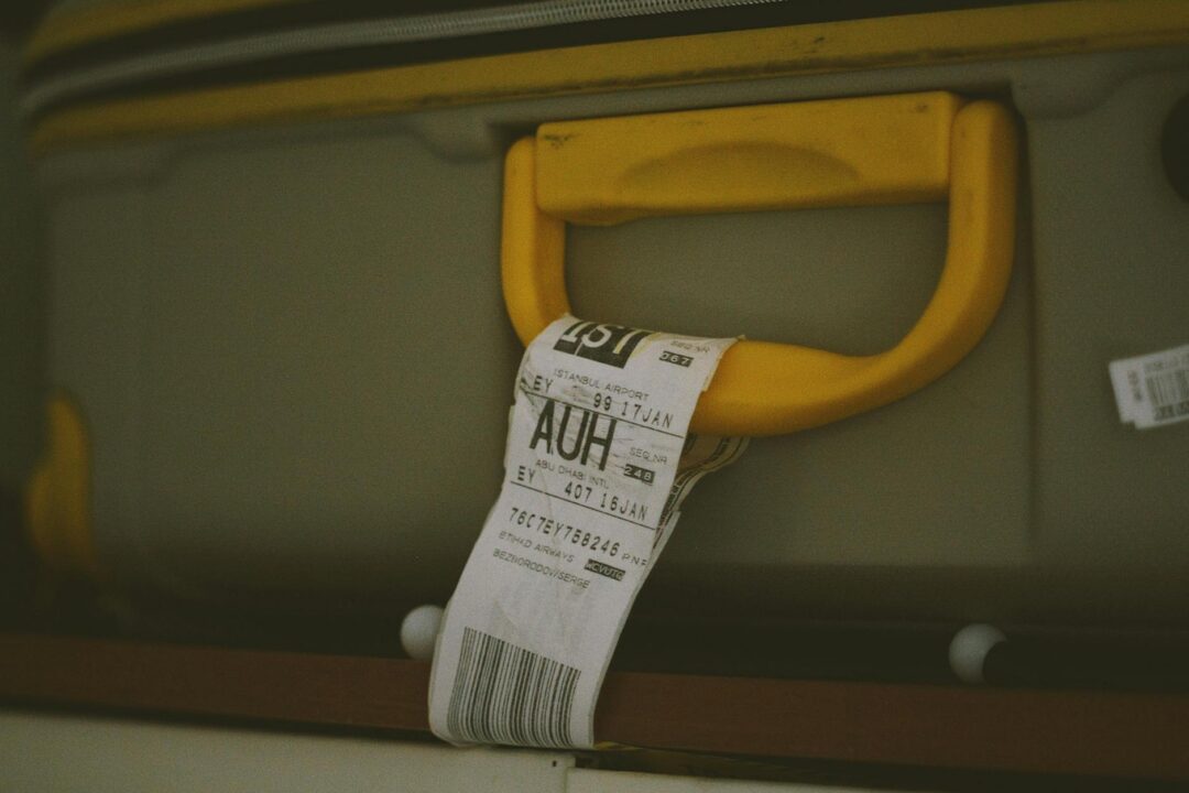 newlywed luggage tags close-up, 'Mr & Mrs' embossed on cream leather luggage tag attached to a carry-on handle