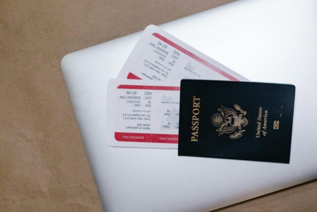 couple planning honeymoon at laptop with passports, travel guides, world map, candid newlywed moment
