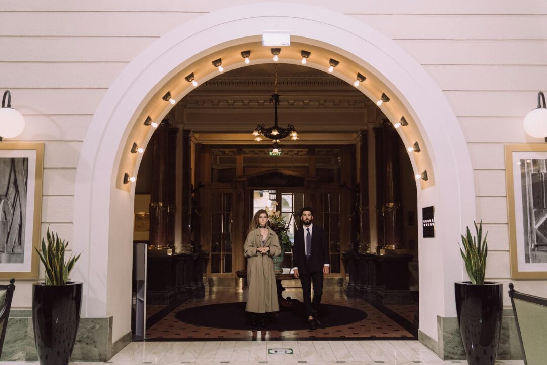 couple receiving hotel welcome amenities, champagne and flowers, at a luxury hotel check-in desk as newlyweds