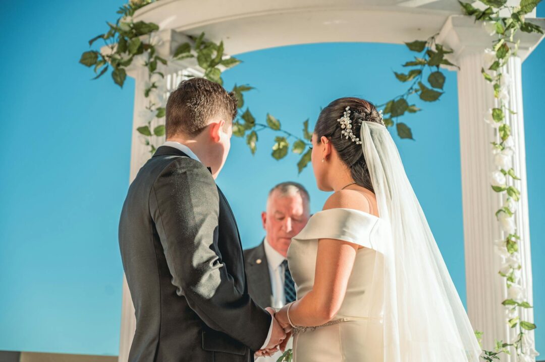 Wedding officiant smiling under floral ceremony arch