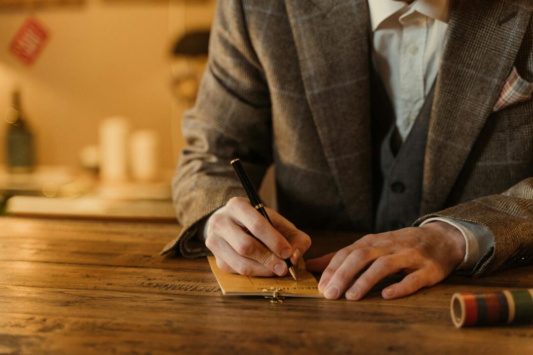 Close-up of a handwritten marriage license on a wooden desk with a pen resting beside it, natural window light, clean and uncluttered compos