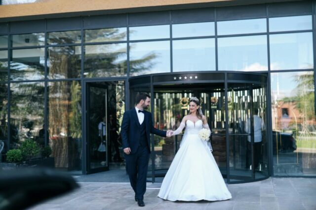 couple arriving at a grand wedding venue entrance - sweeping exterior shot with natural light