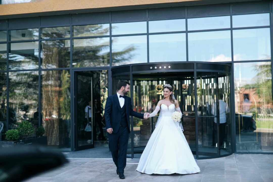 couple arriving at a grand wedding venue entrance - sweeping exterior shot with natural light
