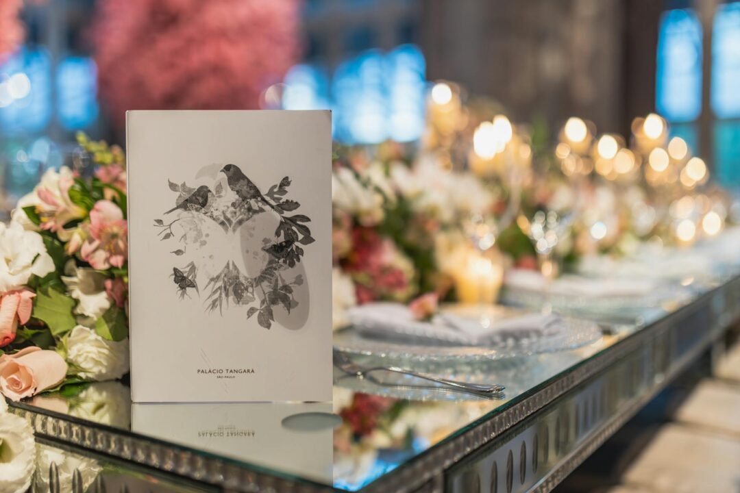 elegant wedding reception tablescape with wedding programs visible on chairs or folded at place settings, warm candlelight