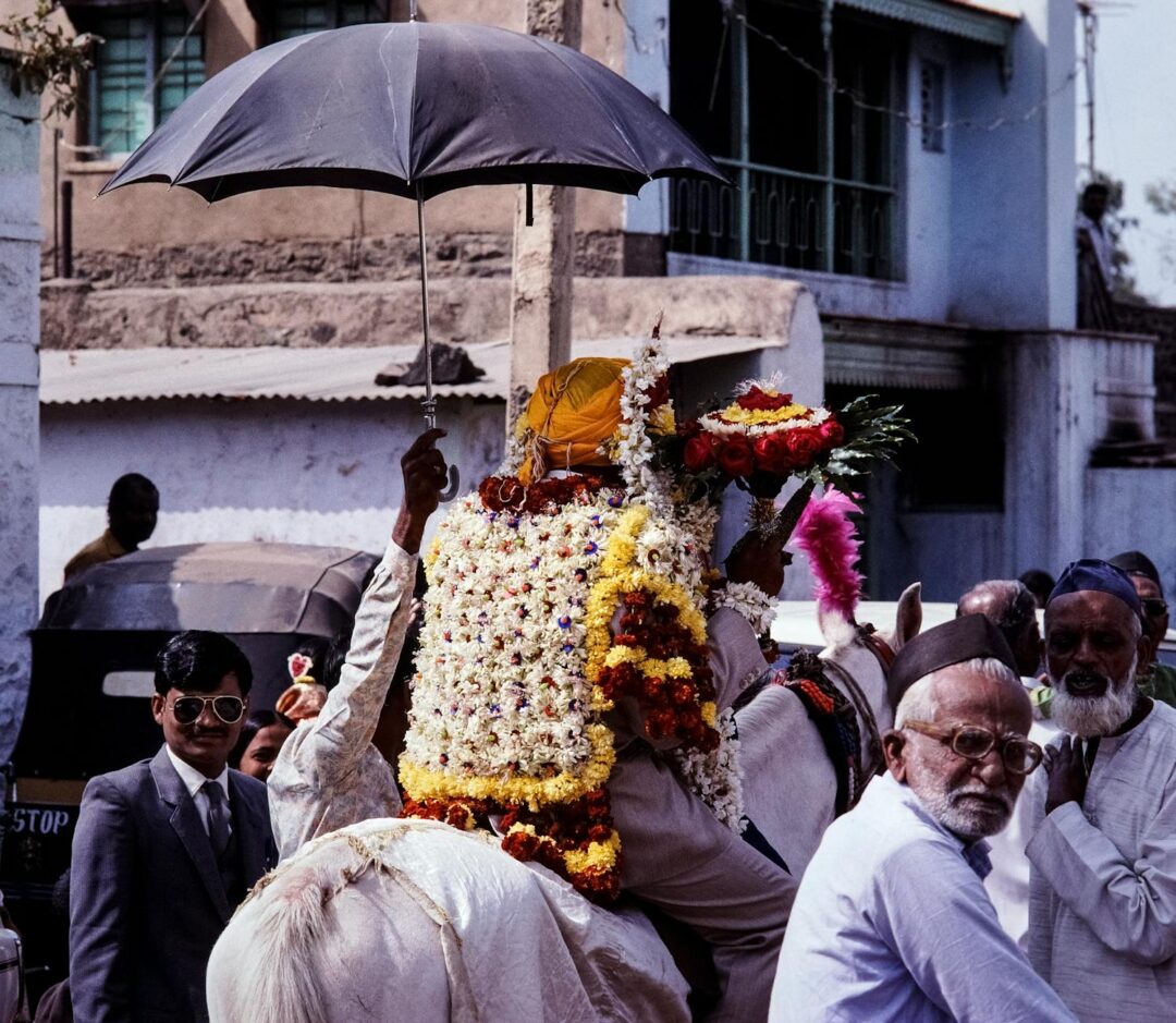 Groom on white horse baraat procession with family