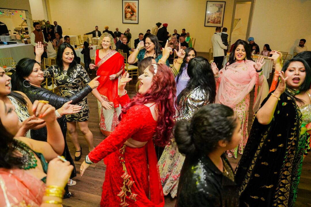 Couple dancing at sangeet night with colorful guests