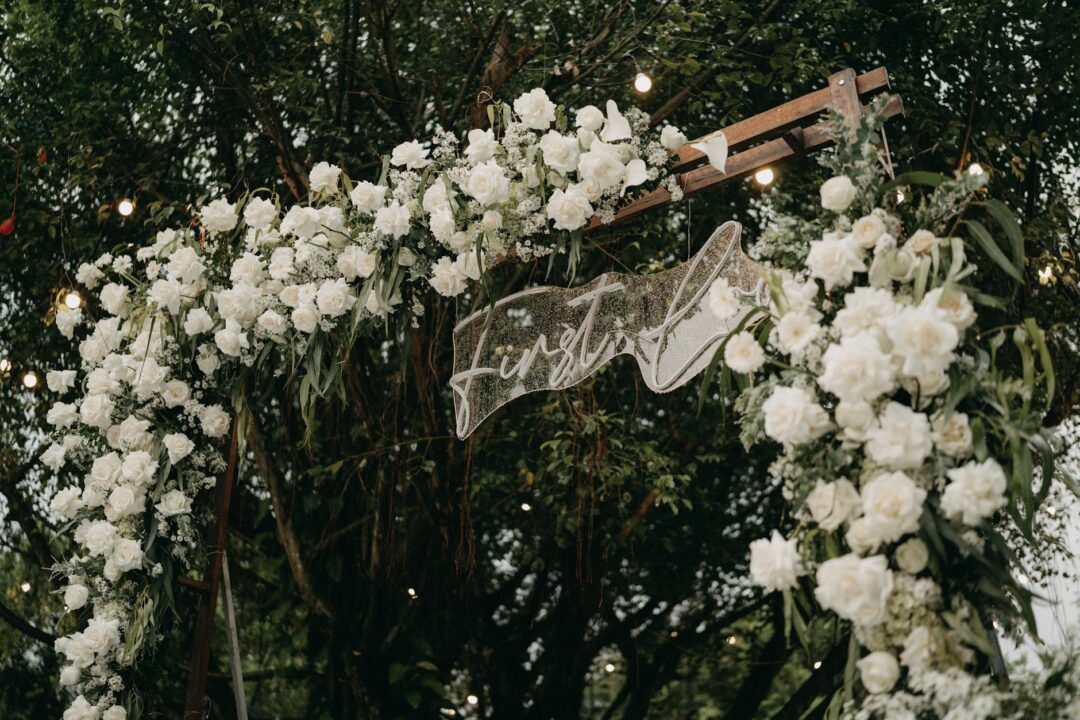 Chuppah canopy decorated with white and blush roses at an outdoor Jewish wedding ceremony, guests seated in rows on either side with soft af