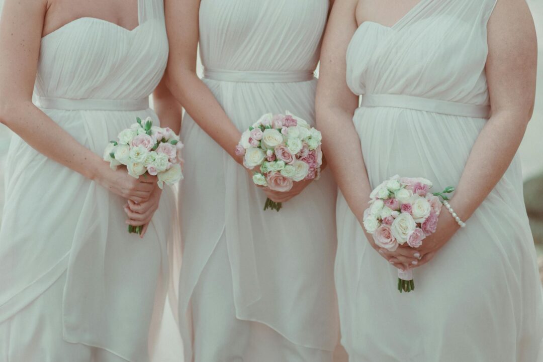 Bridesmaids in soft pastel dresses holding pink and white bouquets at an outdoor wedding, capturing the maid of honor