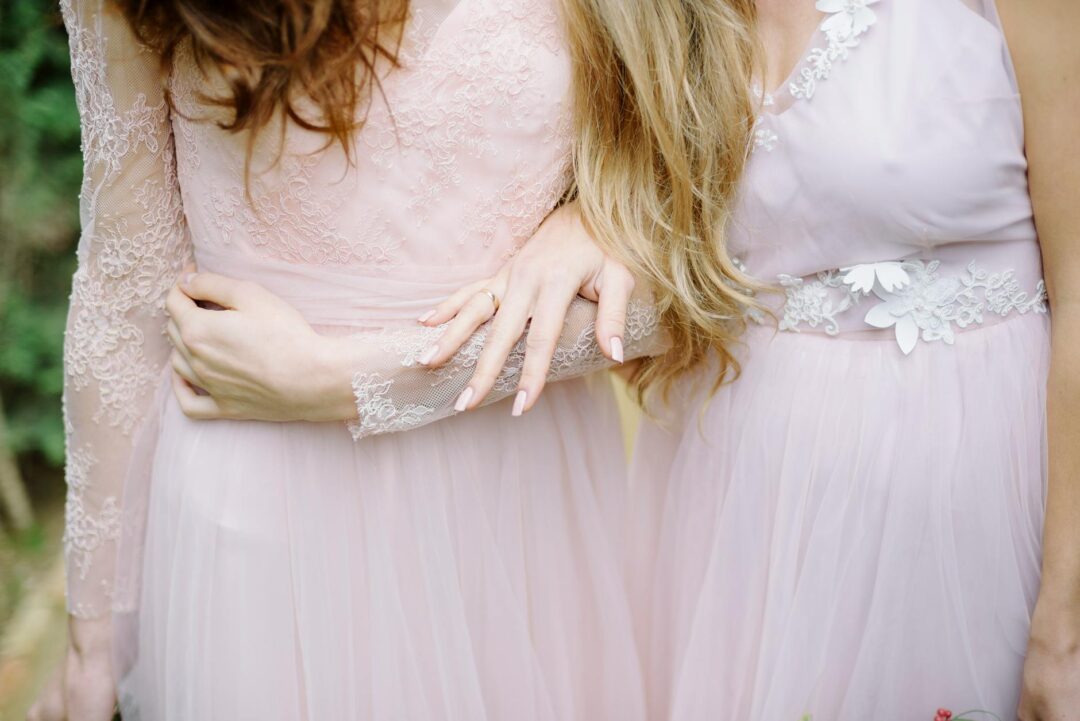 bride and maid of honor laughing together in a sunlit bridal suite while getting ready, champagne flutes in hand, candid moment of pure joy
