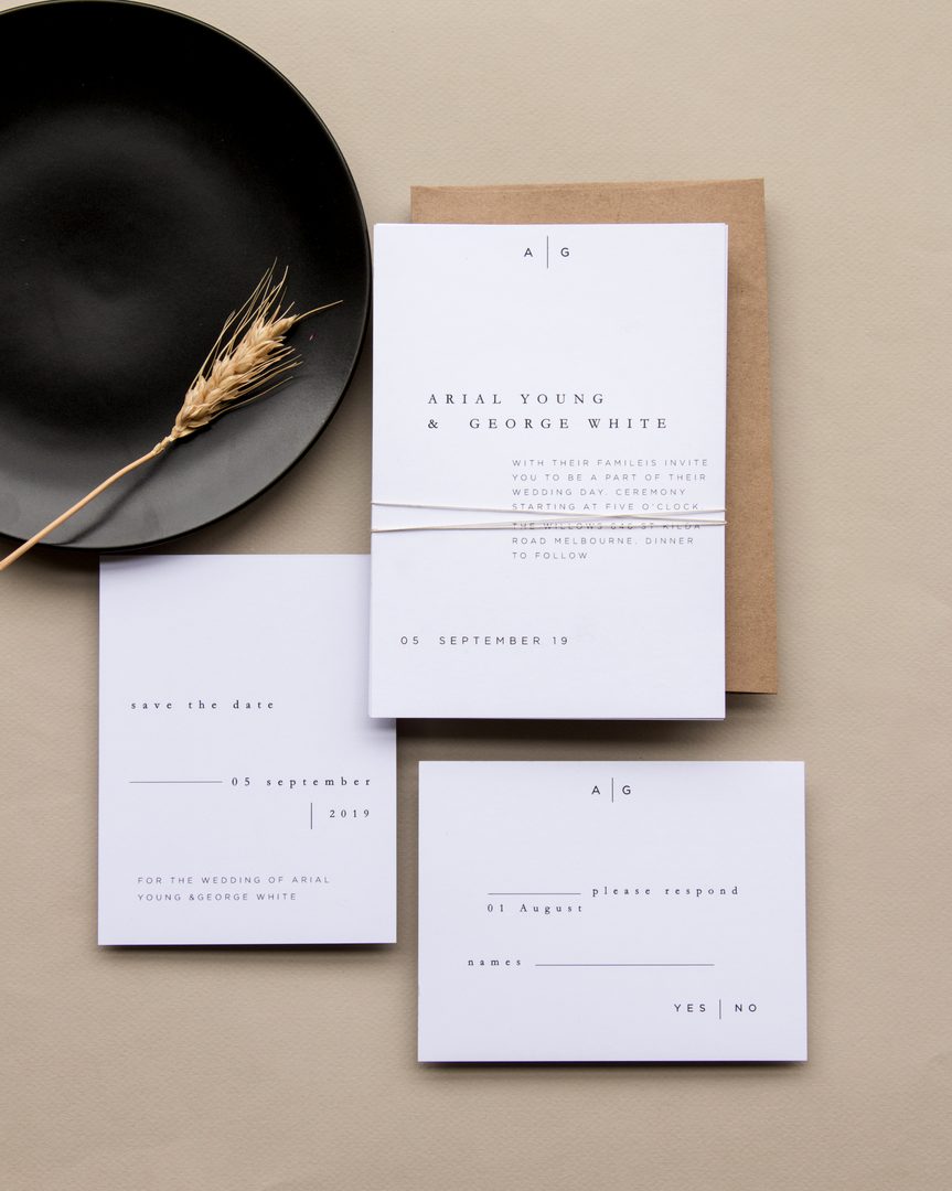 Paperlust rsvp, Beautifully styled minimalist wedding suite flatlay with wheat stalk prop and dark ceramic plate. Contains Australian identifiers: 'St Kilda Road Melbourne' visible on the invitation text.