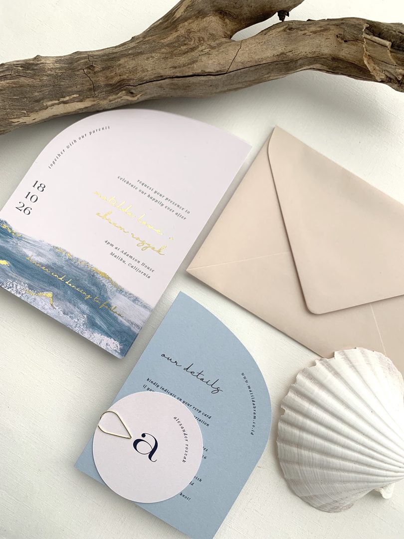 Paperlust rsvp, Beautifully styled coastal wedding suite flat lay featuring arch-shaped invitation with gold foil text
