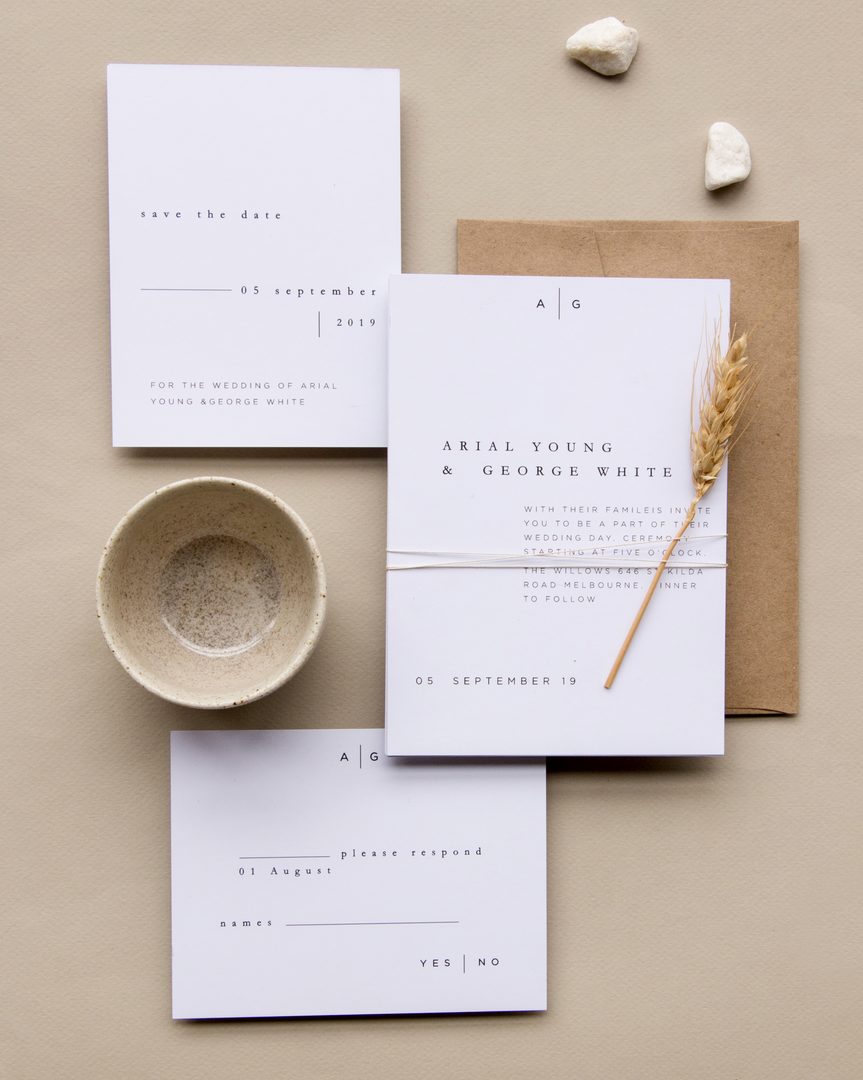 Paperlust rsvp, Beautifully styled minimalist wedding suite flatlay with wheat stalk accent and kraft envelope. Contains Australian identifier 'St Kilda Road Melbourne' on the invitation text.