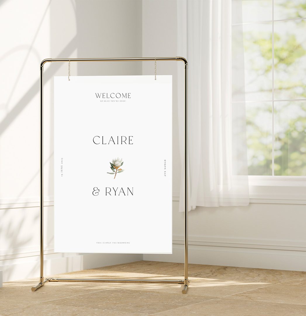 Paperlust welcome sign, Elegant minimalist wedding welcome sign on a gold stand with botanical protea motif. Text reads 'Byron Bay' on the right side