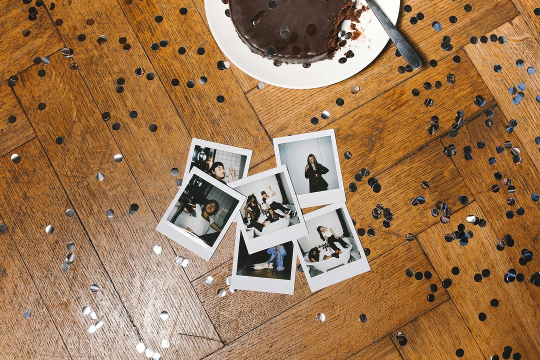 Wedding Photo Booth Ideas: DIY Setup Guide & Inspiration Overhead flat lay of instant photo booth prints scattered with confetti on a dark wood table