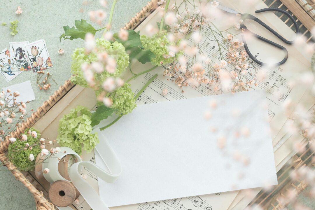 Paperlust elegant invitation suite flatlay with floral botanical motifs, calligraphy script, white and gold color palette on marble surface
