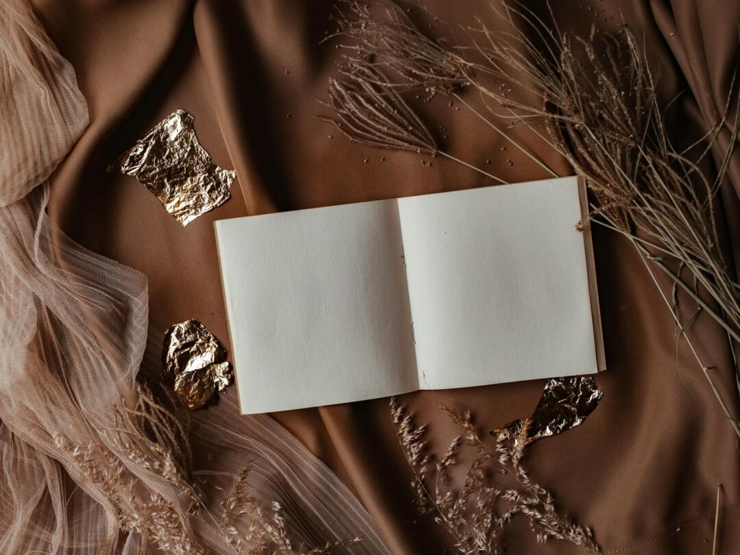 Flat lay of a luxe Paperlust foil wedding invitation suite dressed with satin ribbon bow, wax seal, and vellum wrap on a marble surface - ov