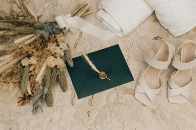 Wedding invitation suite laid flat on a marble surface showing an elegant printed card with coordinating envelope, soft natural light, no te