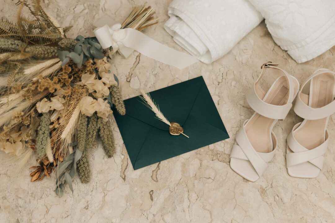 Wedding invitation suite laid flat on a marble surface showing an elegant printed card with coordinating envelope, soft natural light, no te