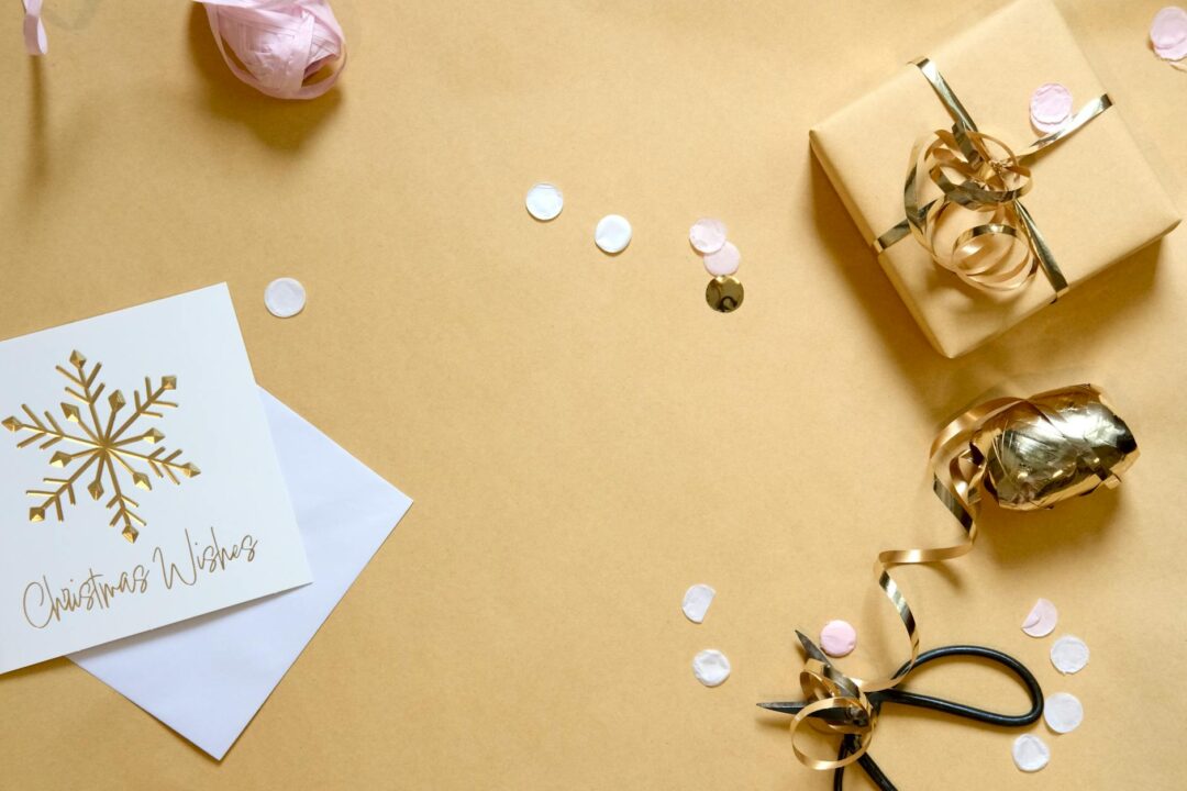 Paperlust Christmas 2022 holiday card with gold flat foil leaf pattern on dark green background, styled with cream envelope on linen surface