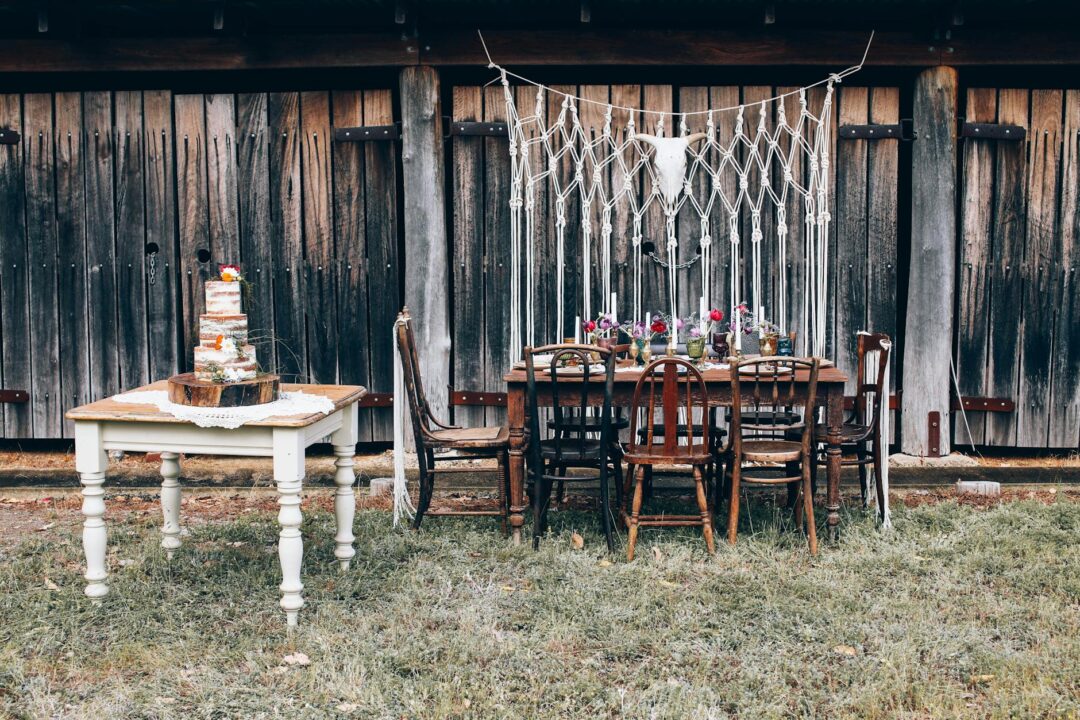 A styled wedding reception table showing table numbers in a wooden holder beside a place card and menu, Paperlust LDBB arch table number car
