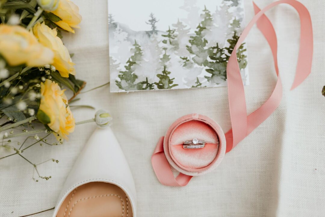 Styled flat lay of a maximalist spring wedding invitation suite featuring a floral wreath design in blush and sage watercolor on cream cotto