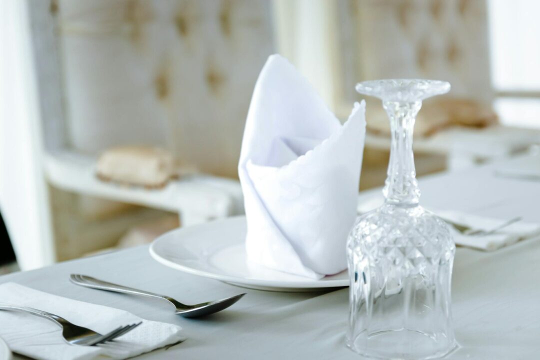 Close-up of an elegant table setting featuring a crystal glass and folded napkin on a plate.