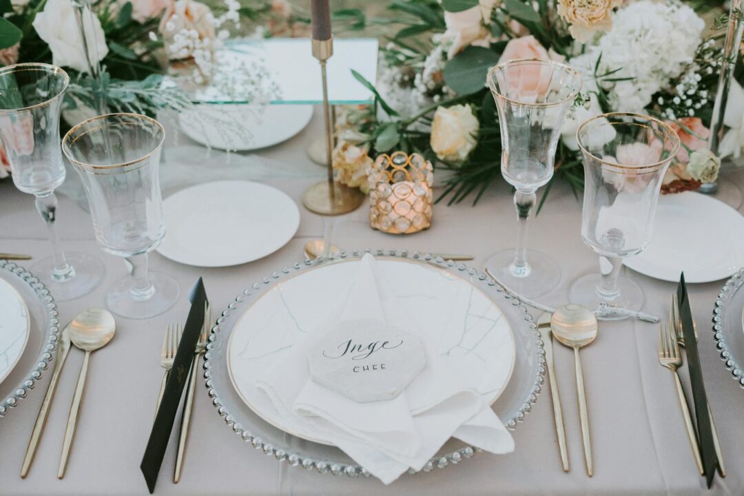 close-up of a formal plated wedding dinner plate with a folded linen napkin and personalized menu card, soft candlelight, white china, gold